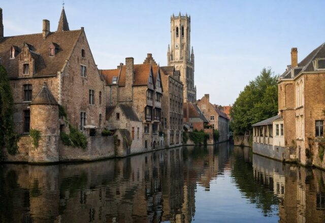 Casas medievais de tijolo e torre do campanário refletidas num canal