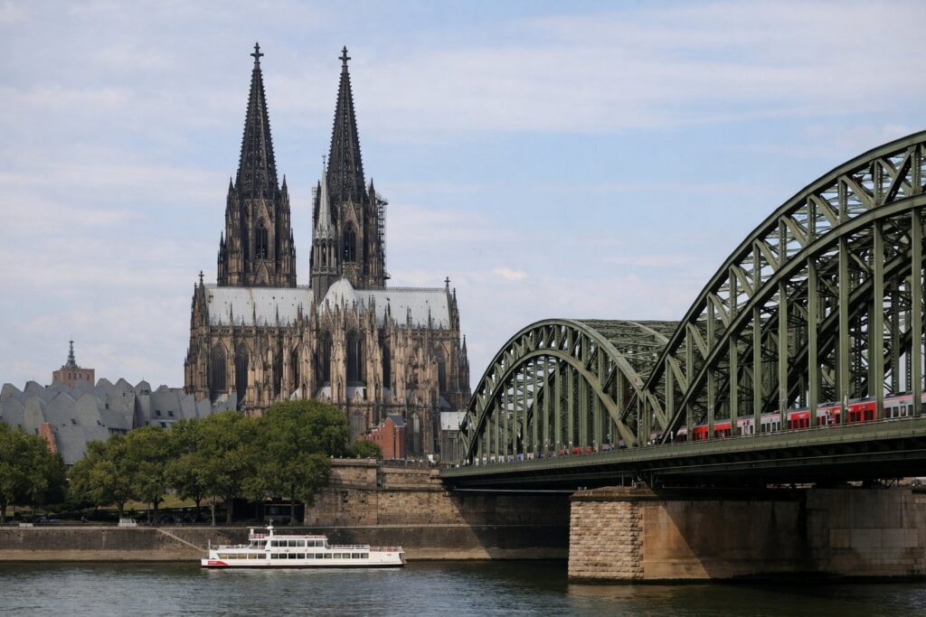 Catedral gótica de duas torres sobre uma ponte ferroviária de aço no Reno